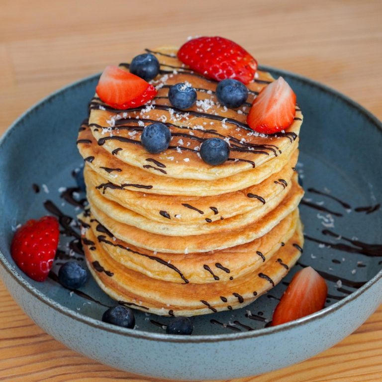 Frische Blaubeeren und Erdbeeren auf Pancakes für eine verhaltensbasierte Esstherapie bei Binge-Eating und Bulimie.